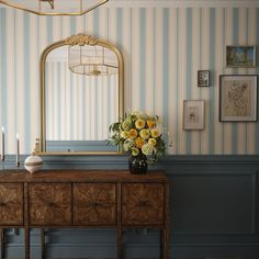 a vase with yellow flowers sitting on top of a wooden table next to a mirror