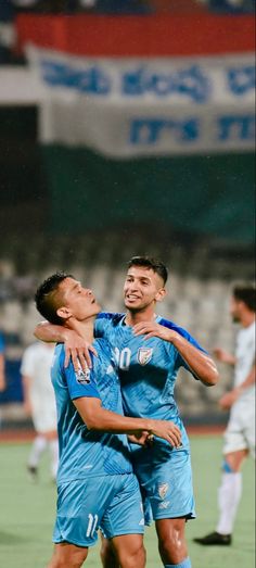 two soccer players are hugging each other on the field