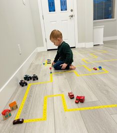 a young boy playing with toy cars on the floor