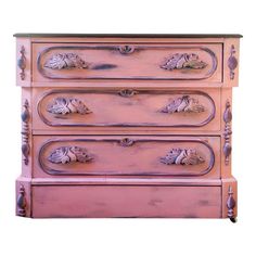 a pink dresser with ornate carvings on the drawers