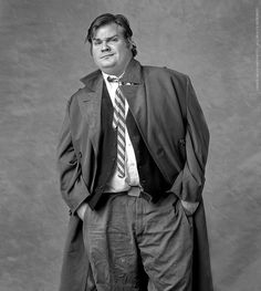 a man in a suit and tie poses for a black and white photo with his hands on his hips