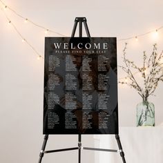 a seating chart is displayed on an easel next to a vase with flowers in it