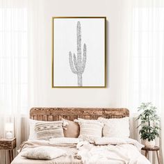 a bed in a bedroom with a cactus print on the wall above it and pillows