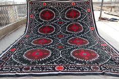 a large black and red blanket sitting on top of a wooden floor next to a fence