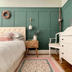 a bedroom with teal walls and white furniture, including a bed in the center