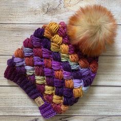 a multicolored knitted hat with a pom - pom on top