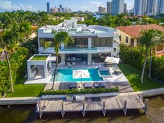 an aerial view of a house with a pool in the foreground and palm trees