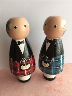 two wooden figurines dressed in tartan and tuxedo, one wearing a bow tie