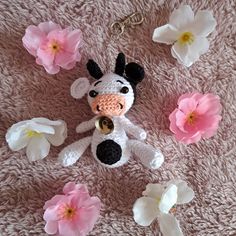 a stuffed cow is surrounded by flowers on the carpet with it's keychain