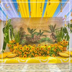 a table with sunflowers and other flowers on it in front of a backdrop