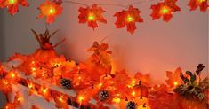 a fireplace decorated with fall leaves and lights