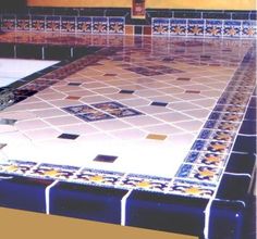 a tiled counter top in a kitchen with blue and yellow tiles on the bottom half