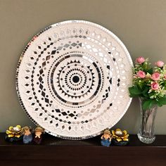 a white plate sitting on top of a wooden table next to a vase with flowers