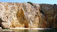 people are swimming in the water near some cliffs