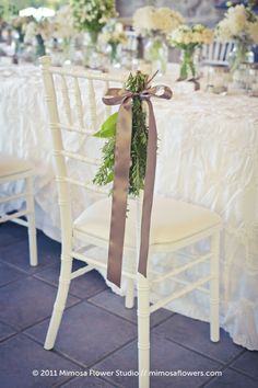 a chair with a bow tied to it sitting next to a table covered in flowers