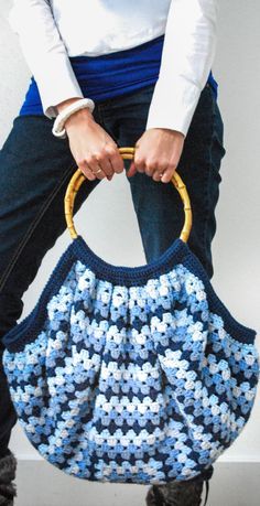 a woman is holding a crocheted purse