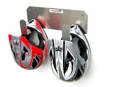 two red and black motorcycle helmets are shown in front of a metal holder on a white background