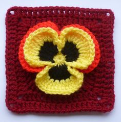 a crocheted square with an orange flower on the front and yellow petals on the back