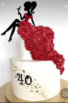 a white cake decorated with red flowers and silhouettes of two people sitting on top