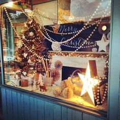 a christmas display in a store window with lights and decorations on the fireplace mantles