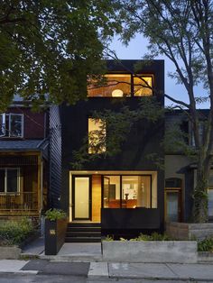 a black house with lots of windows on the front and side of it at night