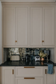 a kitchen with white cabinets and black counter tops