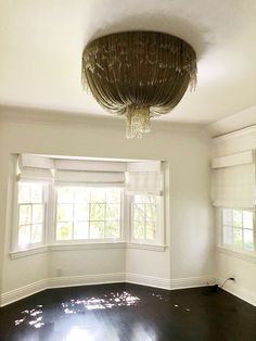 an empty room with a chandelier hanging from it's ceiling and windows