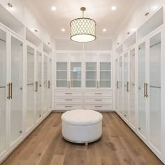 a large walk in closet with lots of white cabinets and glass doors on the walls