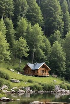 a log cabin sits on the edge of a lake in front of some trees and rocks