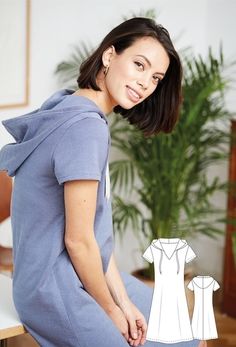 a woman sitting on a table next to a plant wearing a blue dress and smiling