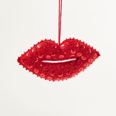 a red ornament hanging from a string on a white wall with the shape of a mouth