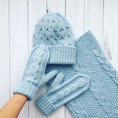 a pair of blue knitted mittens and gloves on top of a white wooden surface