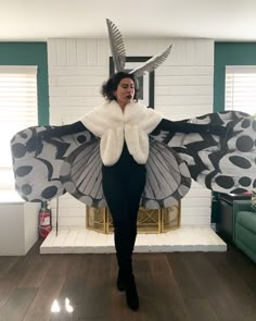 a woman standing in front of a fire place wearing a costume with wings and horns