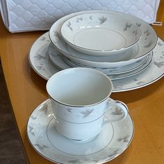 a table topped with plates and cups on top of a wooden table next to a white box