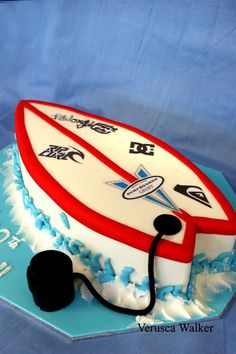 a surfboard cake is decorated with blue and white icing, along with a stethoscope