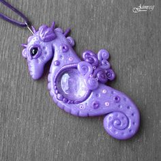 a purple necklace with an animal shaped pendant hanging from it's side on a gray surface