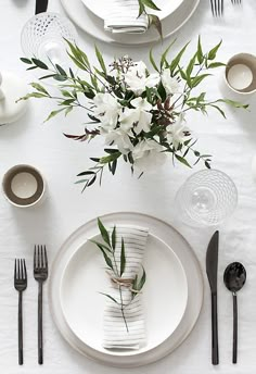 the table is set with black and white place settings, silverware, and flowers