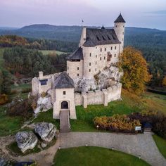 an aerial view of a castle in the middle of trees and grass, surrounded by rocks