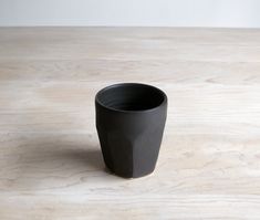 a black cup sitting on top of a wooden table