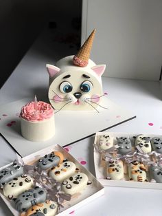 there is a cat cake and cupcakes on the table with it's eyes open