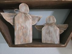 two wooden angel figurines sitting on top of a shelf