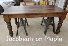 an old wooden table with metal legs on the bottom is sitting in front of a white car