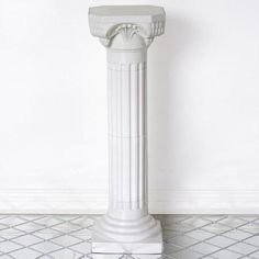 a white pedestal on the floor in front of a wall