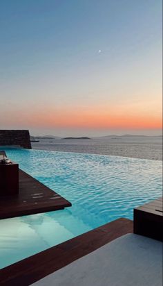 an empty swimming pool with the sun setting in the background