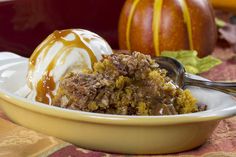 a bowl filled with pudding and ice cream on top of a table next to pumpkins