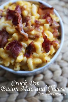 a white bowl filled with macaroni and cheese covered in bacon sitting on top of a table