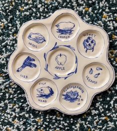 a blue and white plate with six different types of food in it on carpeted area