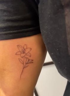 a woman's thigh with a small flower tattoo on her left side ribcage