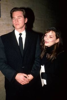 a man in a suit and tie standing next to a woman wearing a black dress