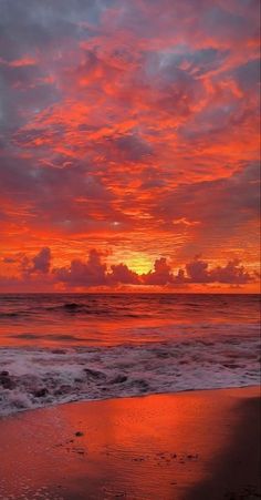 the sun is setting over the ocean with clouds in the sky and water on the beach